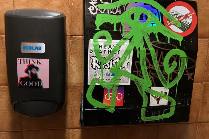 A photo of graffiti and sticker art found in the restroom of LuAnne's Wild Ginger